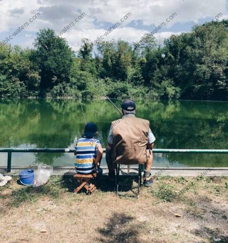 man in black shirt sitting on chair near lake during daytime